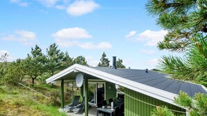 A green wooden cabin with a sloped roof, a satellite dish, and a patio with outdoor seating. - "Tjordis" - 600m to the fjord by Interhome (Hvide Sande)