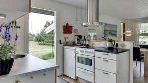 A modern kitchen with white cabinetry, a stainless steel range hood, and a large window offering a view of the outdoors. - "Tjordis" - 600m to the fjord by Interhome (Hvide Sande)