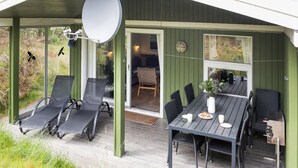 A covered outdoor seating area with a table and chairs, a satellite dish, and a view of the interior. - "Tjordis" - 600m to the fjord by Interhome (Hvide Sande)