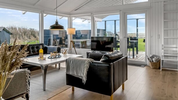 Un vaste espace de vie comprenant une grande table, des sièges confortables, un téléviseur et une vue sur l’extérieur.