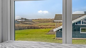 Une chambre avec vue sur un champ verdoyant et un bâtiment doté d’un toit recouvert de tuiles.