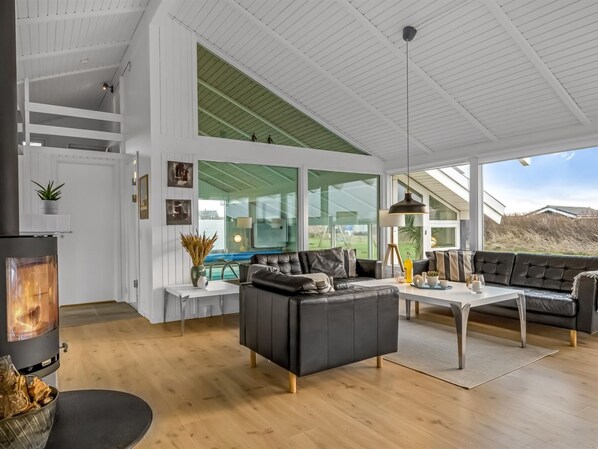 Una sala de estar moderna con chimenea, ventanas amplias y un techo alto.