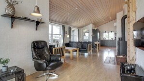 A spacious living area with a leather chair, wooden dining table, and a kitchen in the background. - "Mayke" - 900m from the sea by Interhome (Løkken)