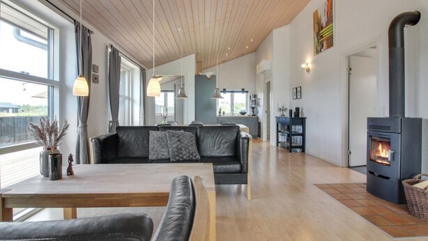 A modern living room with a black leather sofa, a wooden dining table, and a fireplace. - "Mayke" - 900m from the sea by Interhome (Løkken)