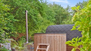 A wooden hot tub on a wooden deck with a ladder, surrounded by greenery and a metal chimney. - "Stefani" - 1km from the sea by Interhome (Ebeltoft)