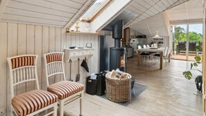 A cozy, open-plan living space with a high ceiling and skylight, wooden furniture, a fireplace, and a dining area with a view of the outdoors. - "Stefani" - 1km from the sea by Interhome (Ebeltoft)