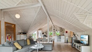 A spacious living area with a high ceiling, a grey sofa, a round coffee table, and a television. - "Stefani" - 1km from the sea by Interhome (Ebeltoft)