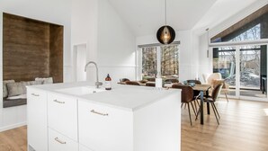 Een moderne keuken met een centraal eiland, een eethoek met een groot raam, en een gezellige zithoek.