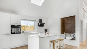 Een moderne keuken met een centraal eiland, witte kastjes en een dakraam.