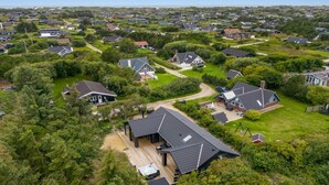 Luchtbeeld van een woonwijk met huizen, groenstroken en een opvallend huis met terras en hottub.