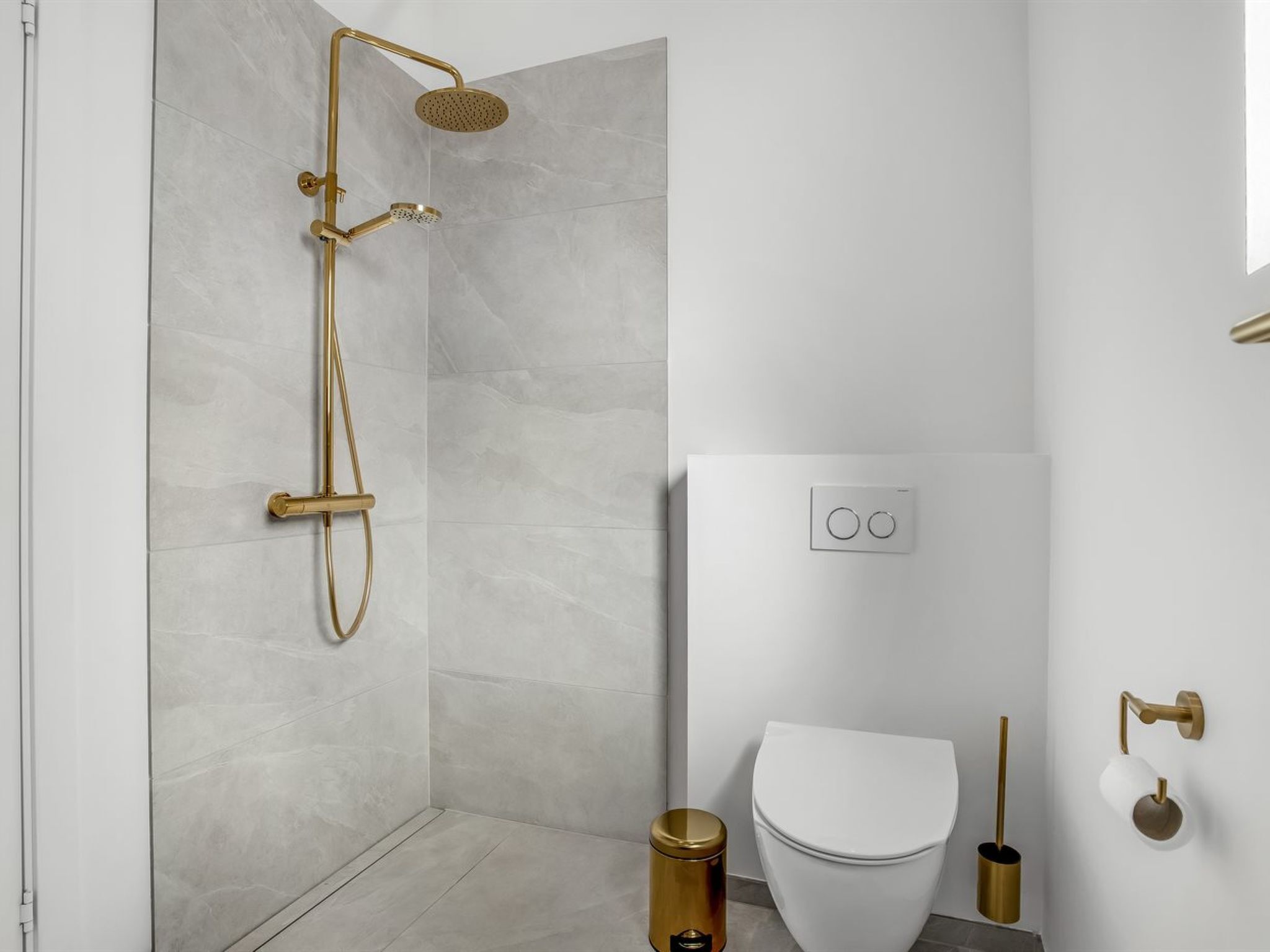 Une salle de bain moderne équipée d’une douche, de toilettes et d’un porte-rouleau de papier toilette fixé au mur.