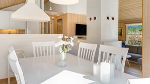 Een moderne eethoek met een witte tafel, stoelen en kaarsen.