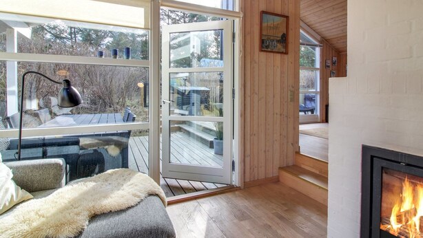 Een gezellige kamer met een open haard, een groot raam en een terras.