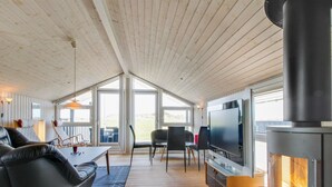 A cozy cabin interior with a fireplace, a TV, and a dining area.