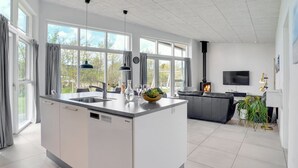 Een moderne keuken met een centraal eiland, grote ramen en een ingebouwde open haard.