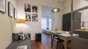 Un espacio habitable moderno y funcional con sofá, mesa de comedor y zona de cocina.