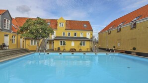 Une piscine avec un bâtiment jaune en arrière-plan.