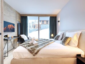 Een moderne hotelkamer met een groot bed, een bureau, een stoel en uitzicht.