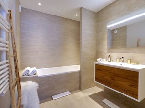 Een moderne badkamer met een badkuip, wastafel en een grote spiegel.