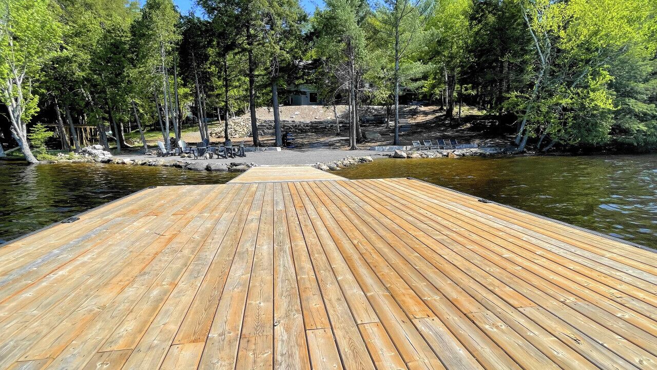 Une jetée en bois s’étendant sur une étendue d’eau calme, entourée d’arbres.