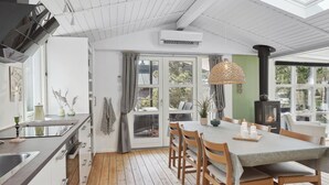 A modern kitchen with a dining area, wooden flooring, and a skylight.