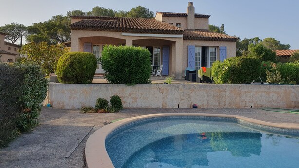 Ein mediterranes Haus mit Schwimmbad, umgeben von gepflegten Hecken und einer Steinmauer.