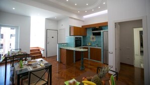 A modern kitchen with wooden cabinets, a central island, and a dining area with a table and chairs. - Divina Salerno (Salerno)