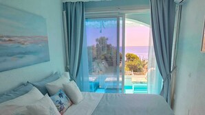 Ein Schlafzimmer mit einem großen Bett, Meerblick und einem Balkon mit Pool.