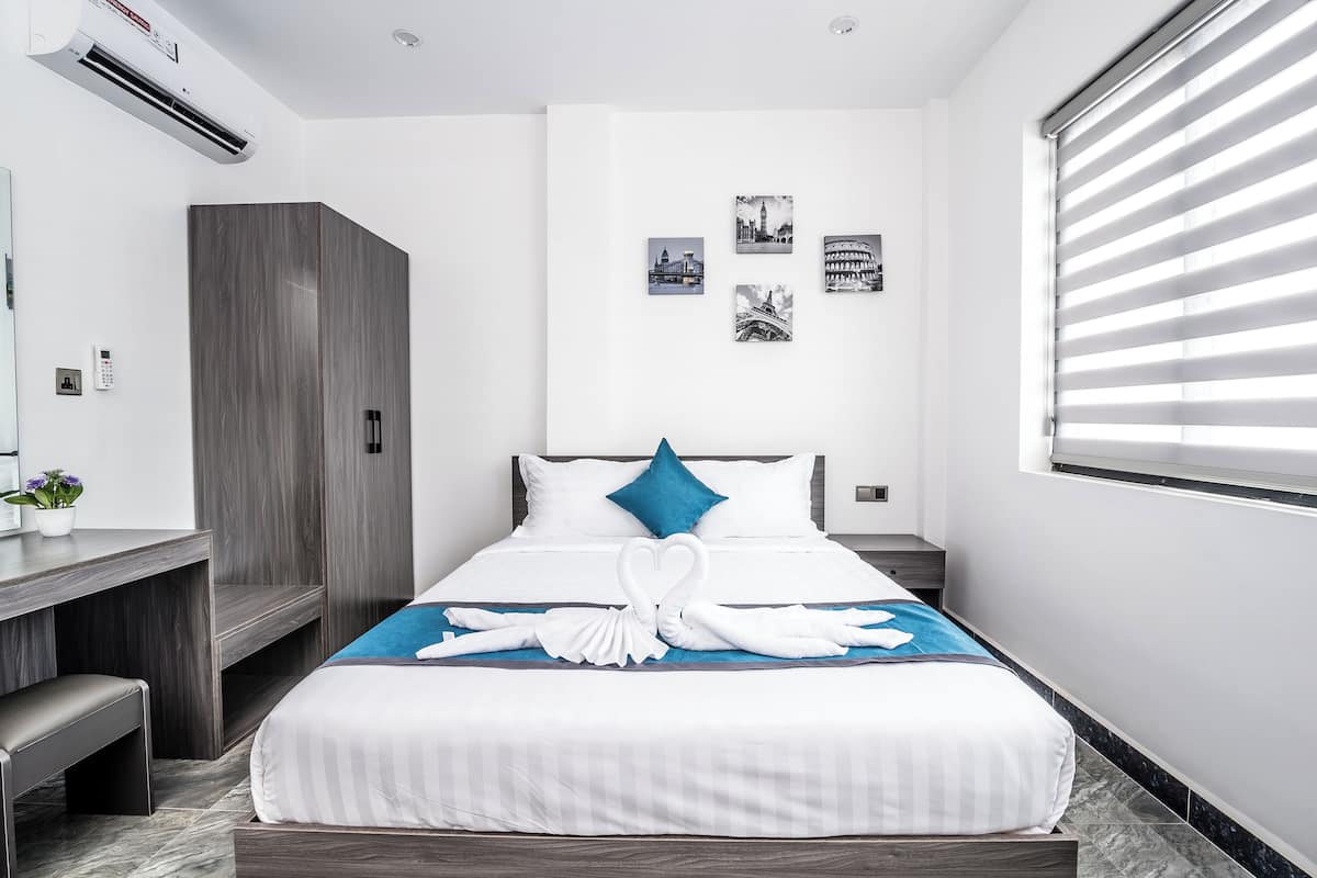 A modern hotel room with a bed, a desk, and a wardrobe.