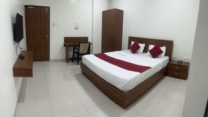 A hotel room with a wooden bed, a desk, a chair, a wardrobe, and a television. - Shelke Mama's Lodging & Resorts (Chhatrapati Sambhajinagar)
