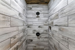 A room with a rustic wooden wall design, a circular ceiling vent, and a black circular object on the floor.