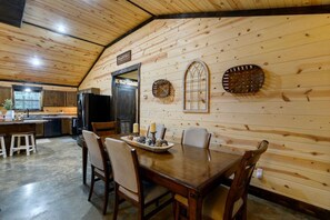 A wooden interior with a dining table, chairs, and a kitchen area. - Makin Time · Air Hockey | Game System | Hot Tub | Near Kayaking (Broken Bow)