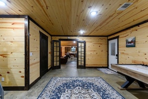 A wooden interior with a hallway leading to a dining area, a bench, and a patterned rug.