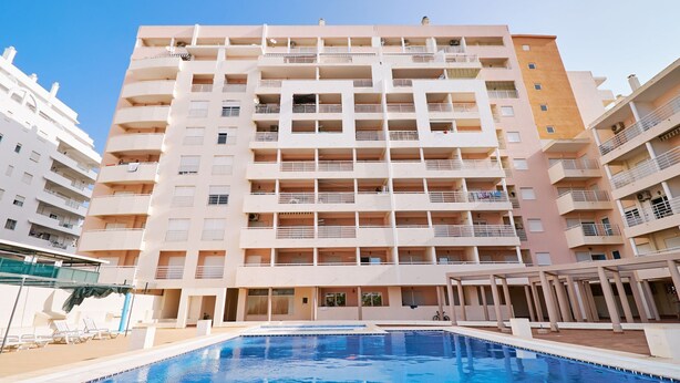 Un hôtel à plusieurs étages avec une piscine en premier plan.