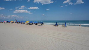 A beach with rows of sun umbrellas and lounge chairs. - Duneside Unit 302 - Oceanfront (Murrells Inlet)