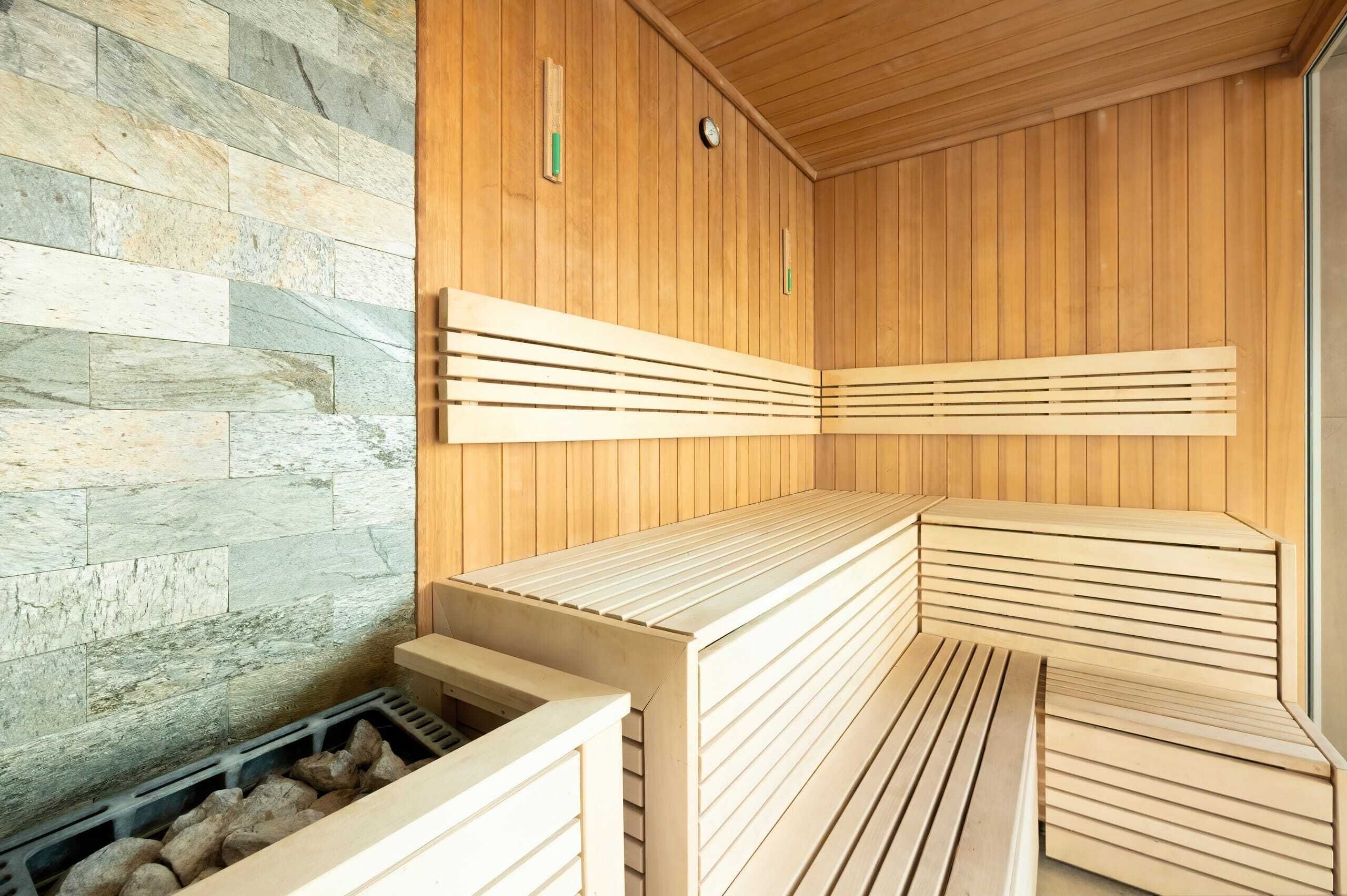A sauna with wooden benches and a stone wall.