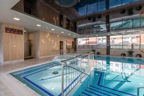 Swimmers can enjoy a refreshing dip in the rectangular pool surrounded by a glass barrier.