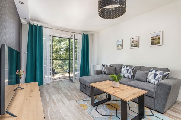 A bright living room with a large sectional sofa, a wooden coffee table, and modern decor, offering a comfortable and stylish relaxation area.