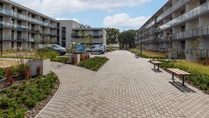 A modern apartment complex with a central courtyard, paved walkways, and outdoor seating areas.