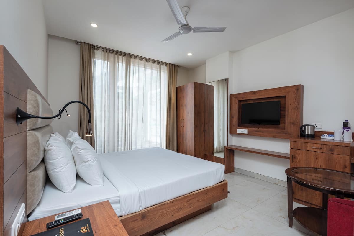 Une chambre d’hôtel équipée d’un lit, d’une télévision, d’une armoire en bois, d’un bureau et d’un ventilateur de plafond.