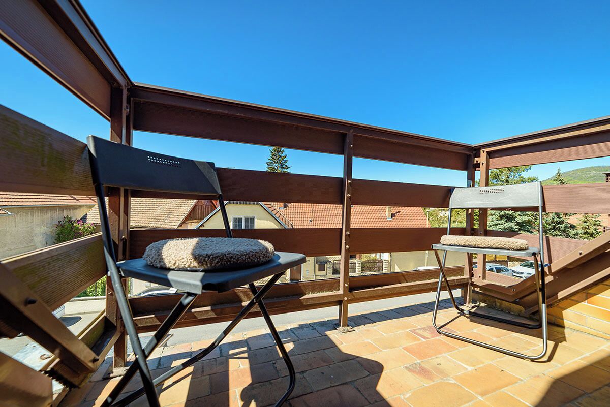 A balcony with a wooden pergola, a folding chair, and a small table.