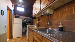 A kitchen with wooden cabinets, a stainless steel sink, and a microwave. - Spacious Family Cottage Near Prague – Pool, Sauna, Garden & Great Day Trips (Mneteš)