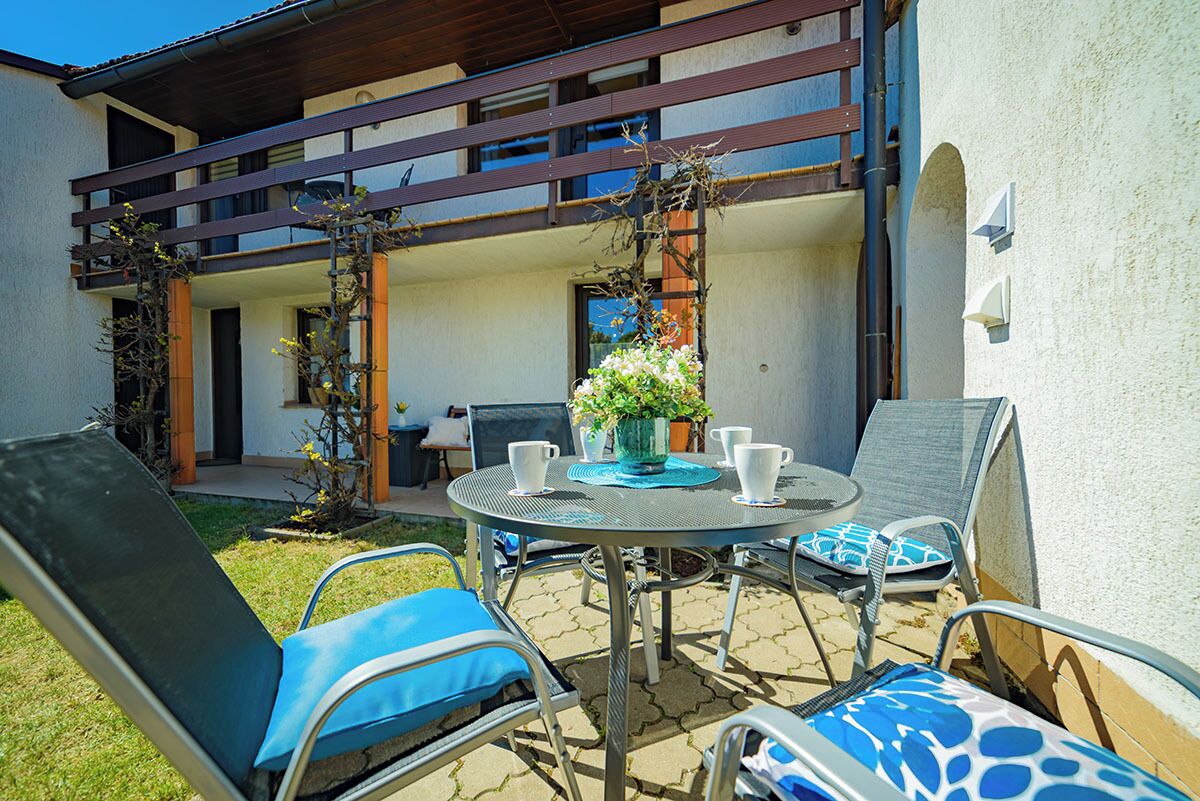 Un patio al aire libre con una mesa redonda, sillas y una planta en maceta.