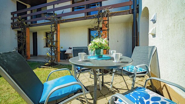An outdoor patio with a round table, chairs, and a potted plant. - Spacious Family Cottage Near Prague – Pool, Sauna, Garden & Great Day Trips (Mneteš)