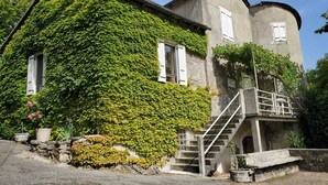 Une maison à deux étages avec un escalier en pierre menant à un balcon.