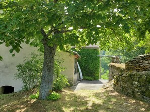 A narrow pathway leading to a building with a stone wall and a green ivy-covered wall. - Château en Cévennes (Rousses)