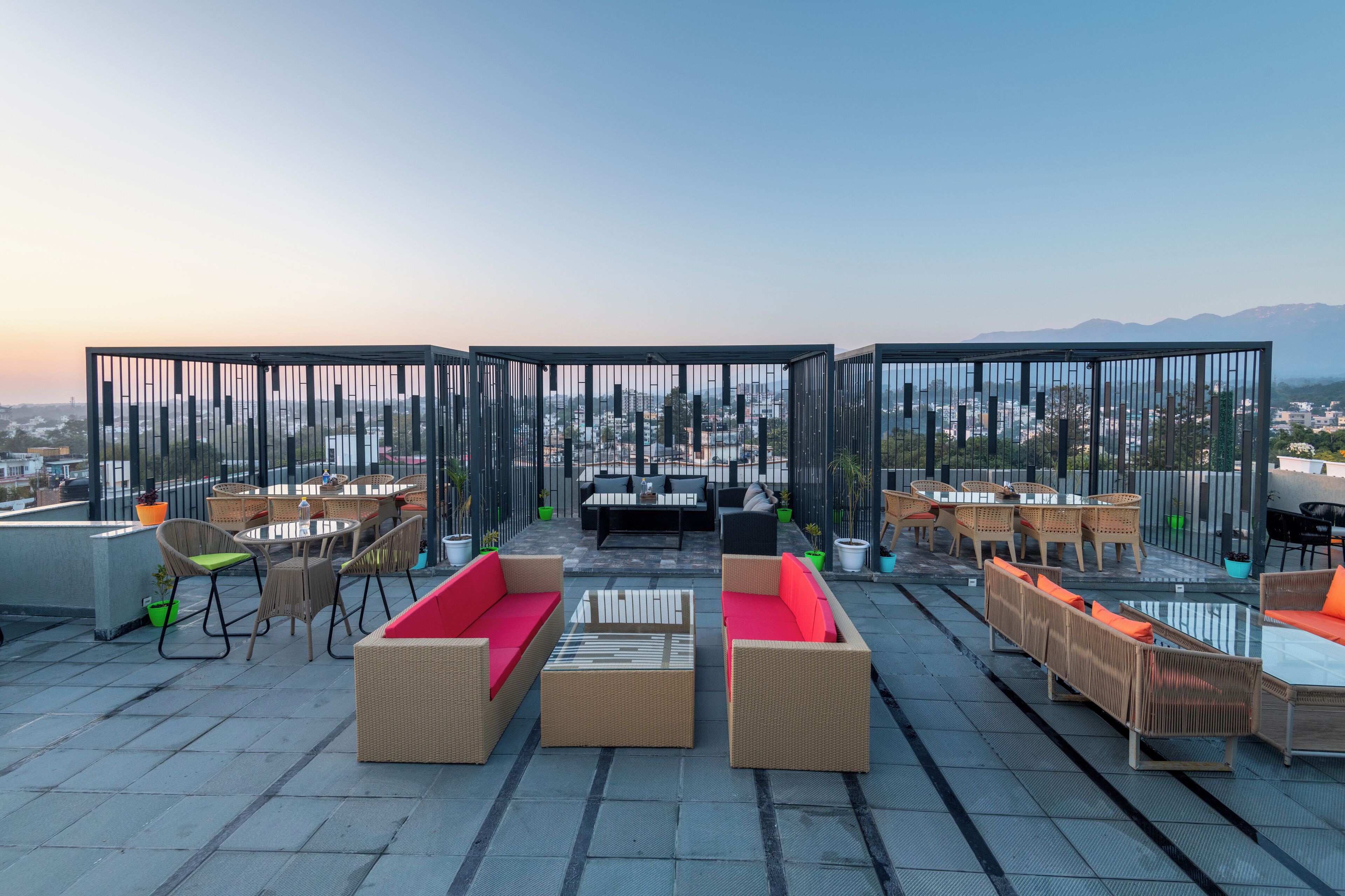 A rooftop terrace with outdoor furniture, a view of the city, and mountains in the distance.