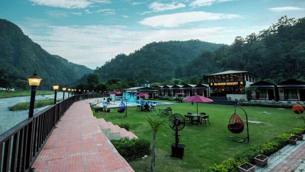 A riverside resort with a paved walkway, outdoor seating, and a swimming pool. - MJ River Resort By DLS Hotels (Yamkeshwar)