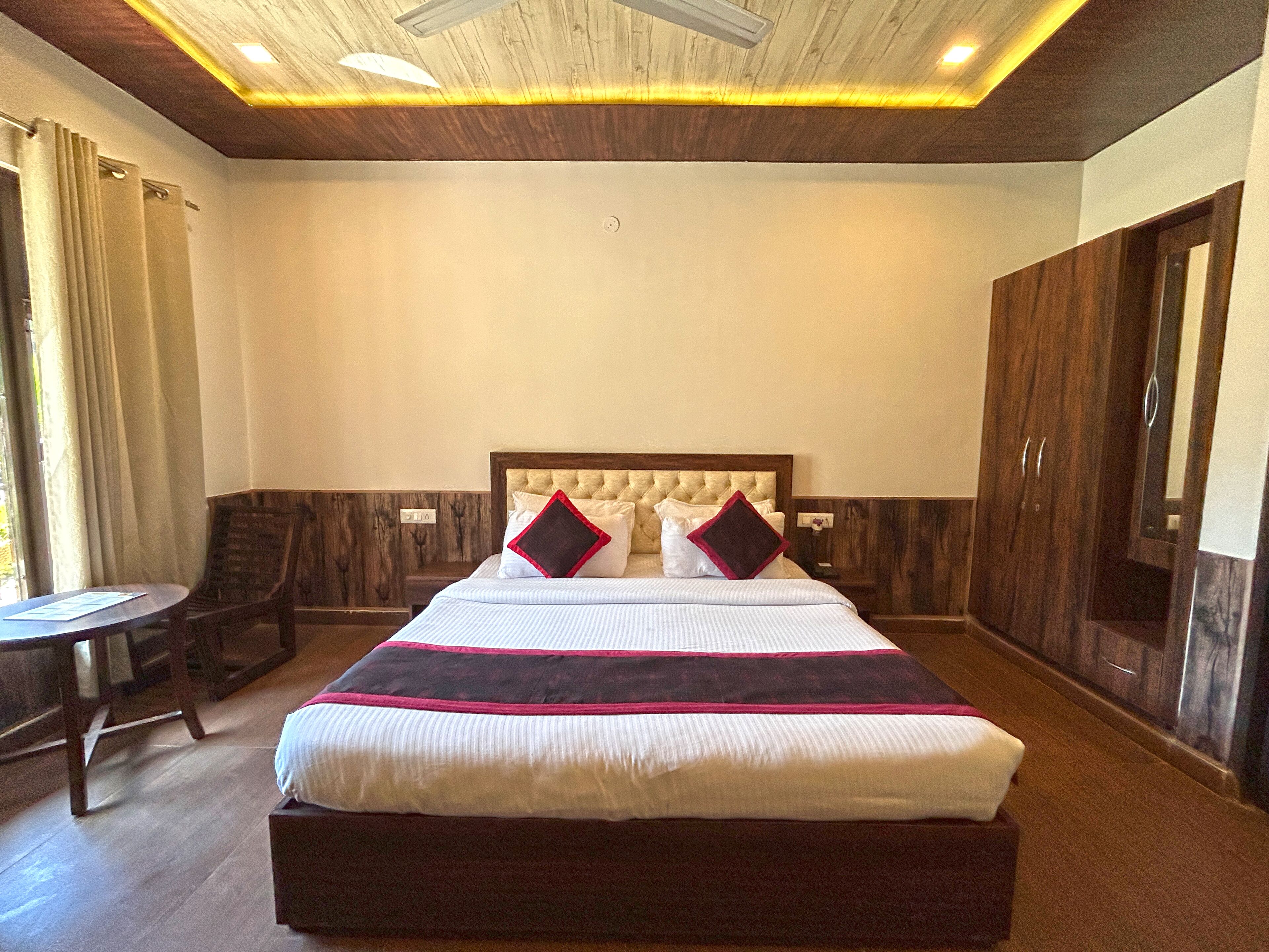 A hotel room with a large bed, a wooden headboard, a desk, and a wardrobe.