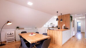 Une cuisine moderne avec des meubles en bois, un îlot central et un coin repas comprenant une table et des chaises en bois.
